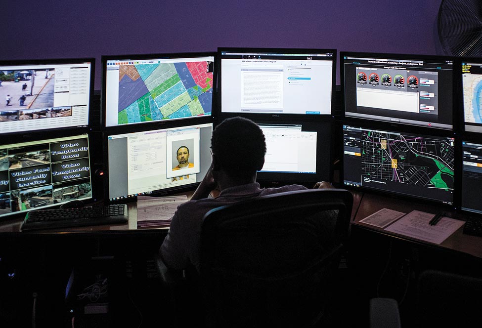 Man at desk studying a rows of computer monitors