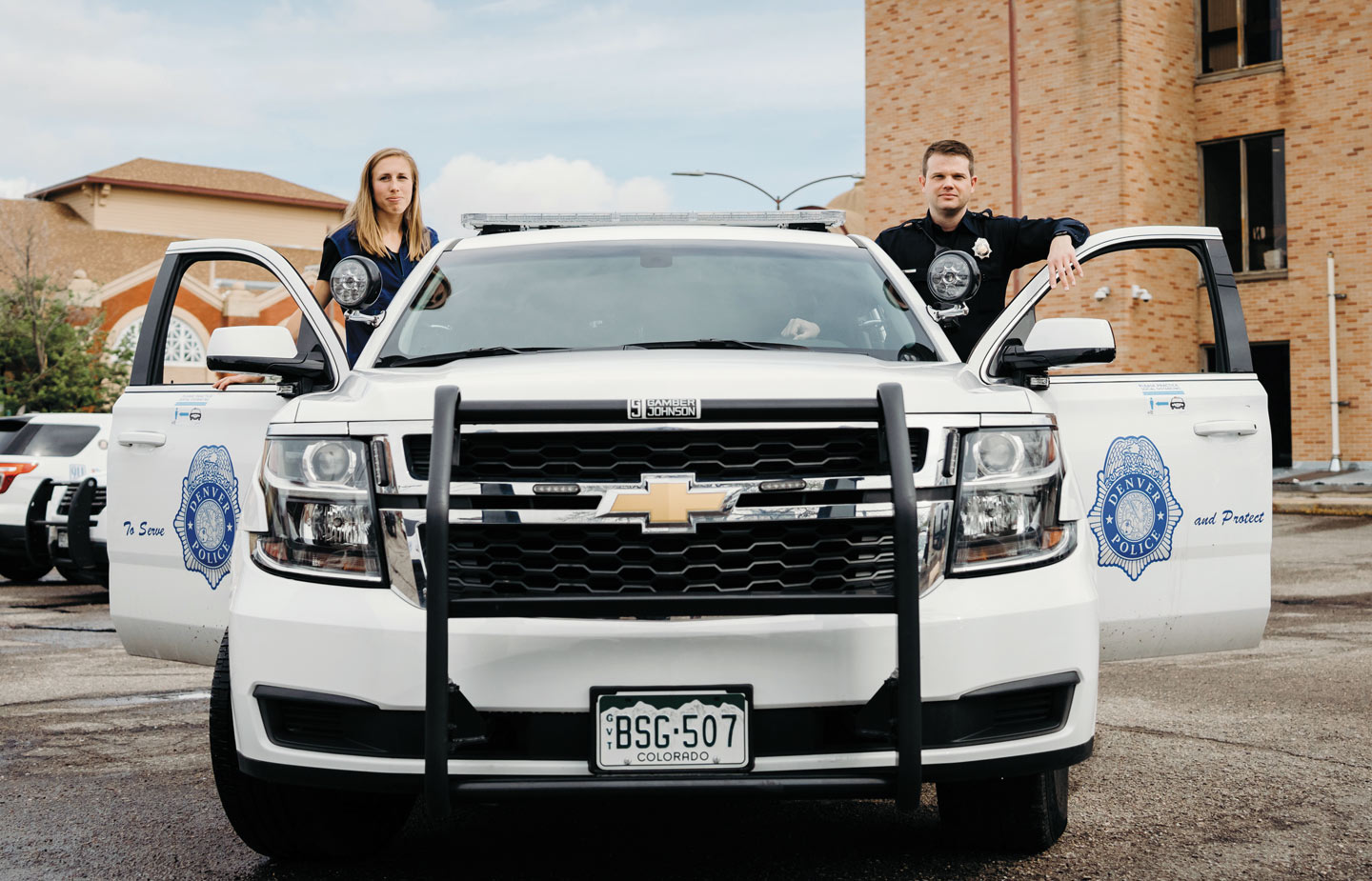 Image of Kathy Evans ’14 and a police officer standing by a patrol car