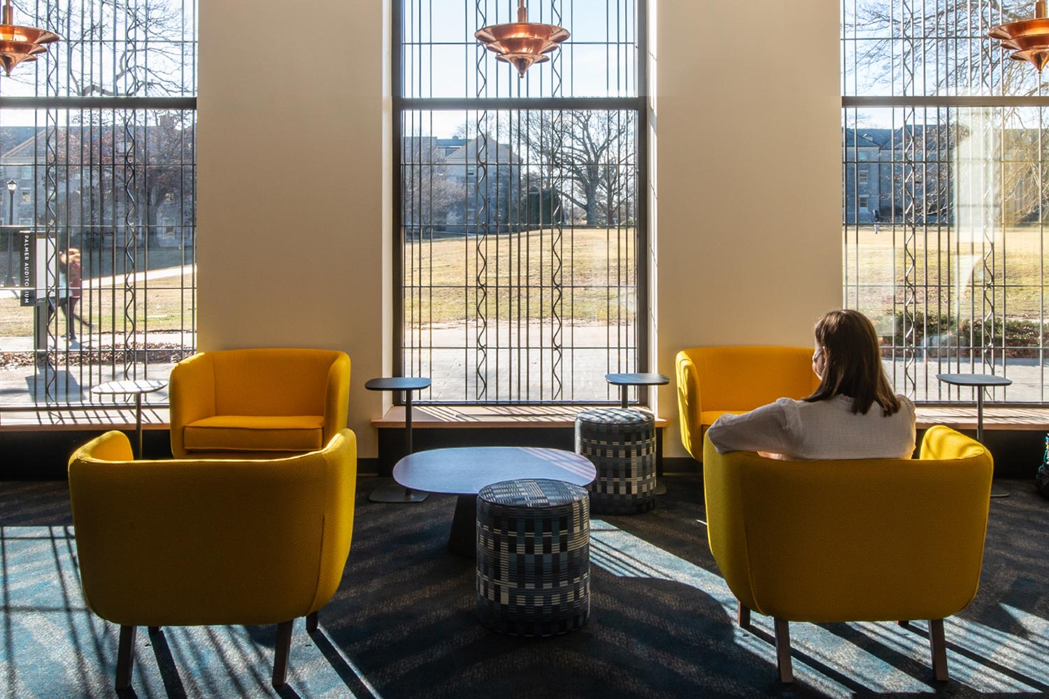 Student looking out of the green-side windows of the new Athey Center