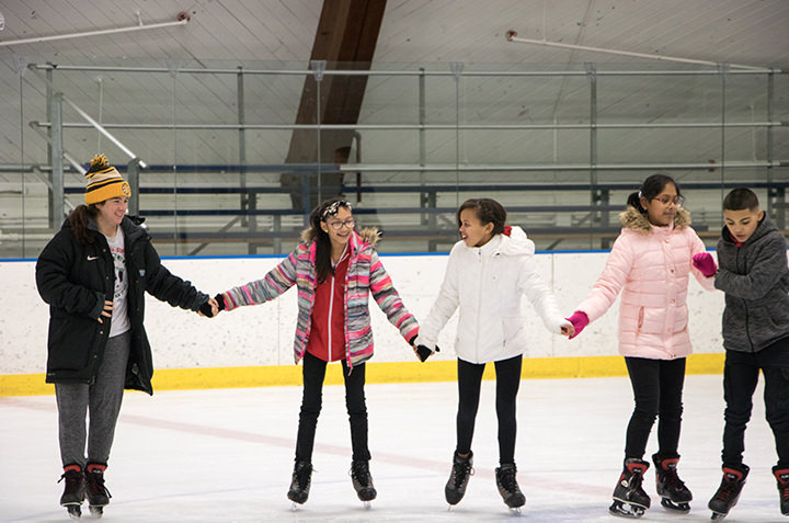 A Conn student skates with seventh grades from New London through Conn's Learn to Skate program.