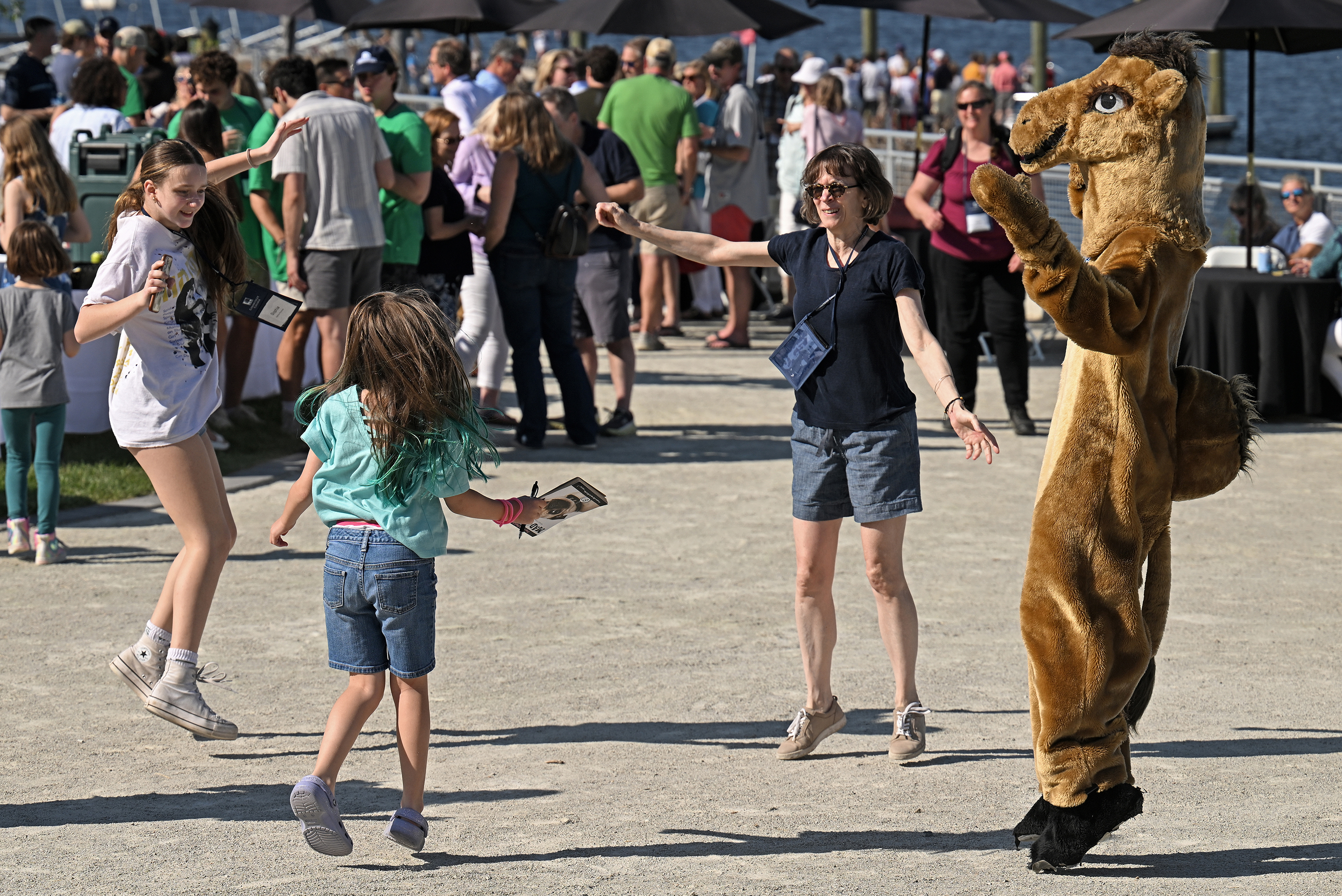 A group of children dance with a camel mascot