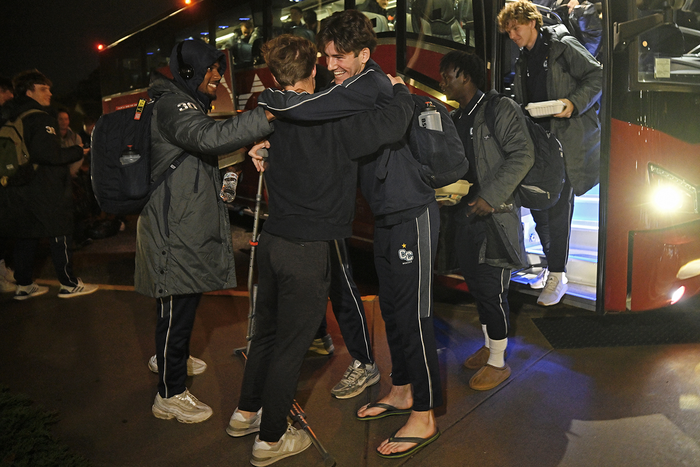 Soccer players are greeted as they disembark from their bus from a victorious tournament.