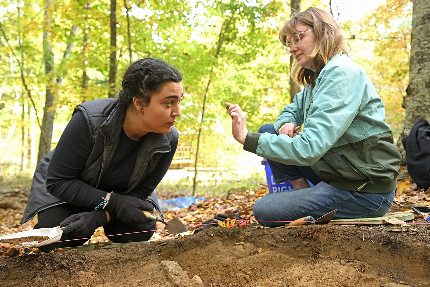 Two archeology students examine a small artifact found in their dig.