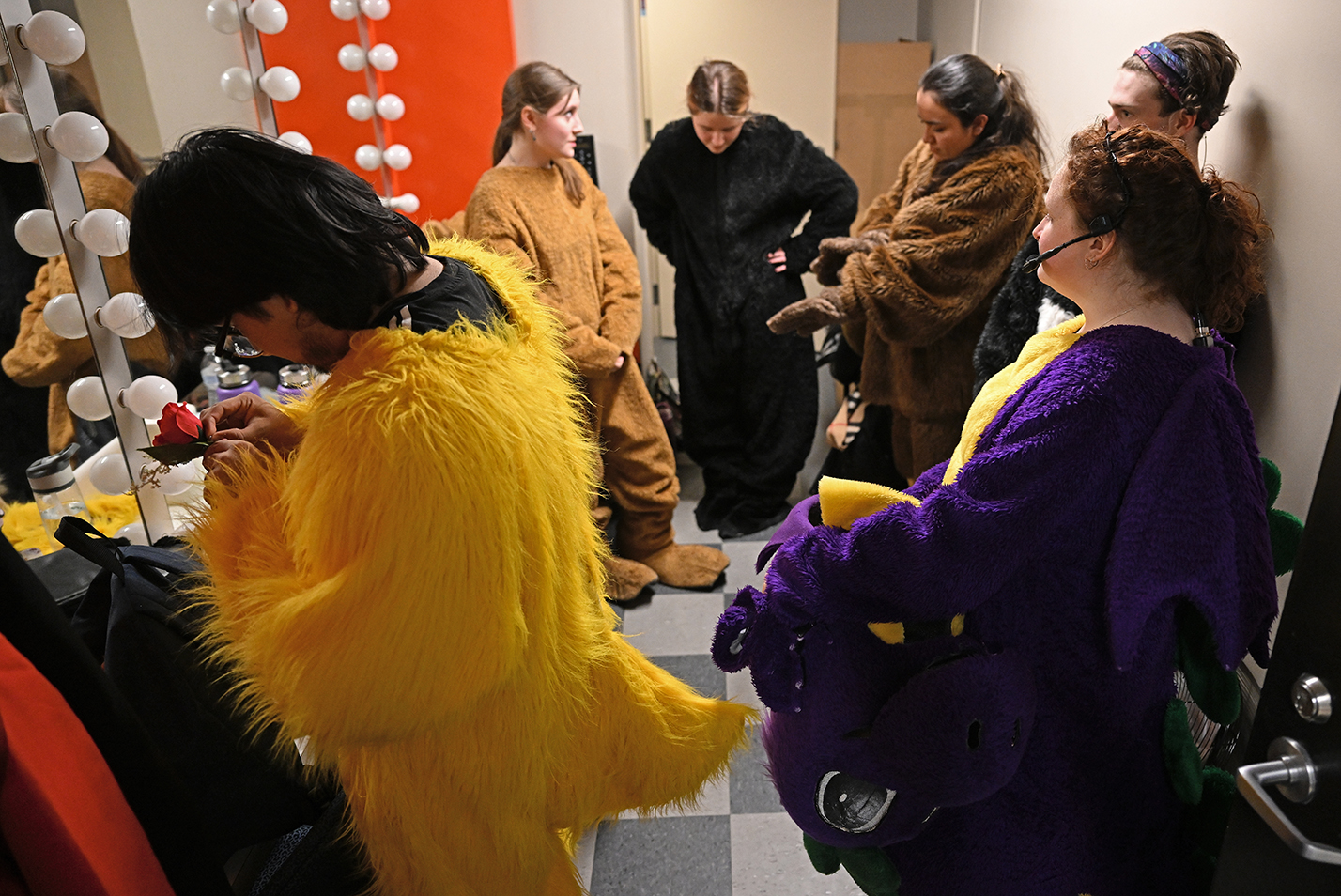 Students in mascot costumes prepare in the dressing room for a singing competition.